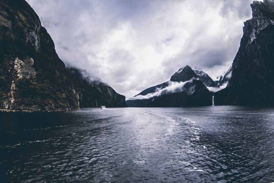 Breathtaking view of Milford Sound fjord with dramatic clouds and serene waters.